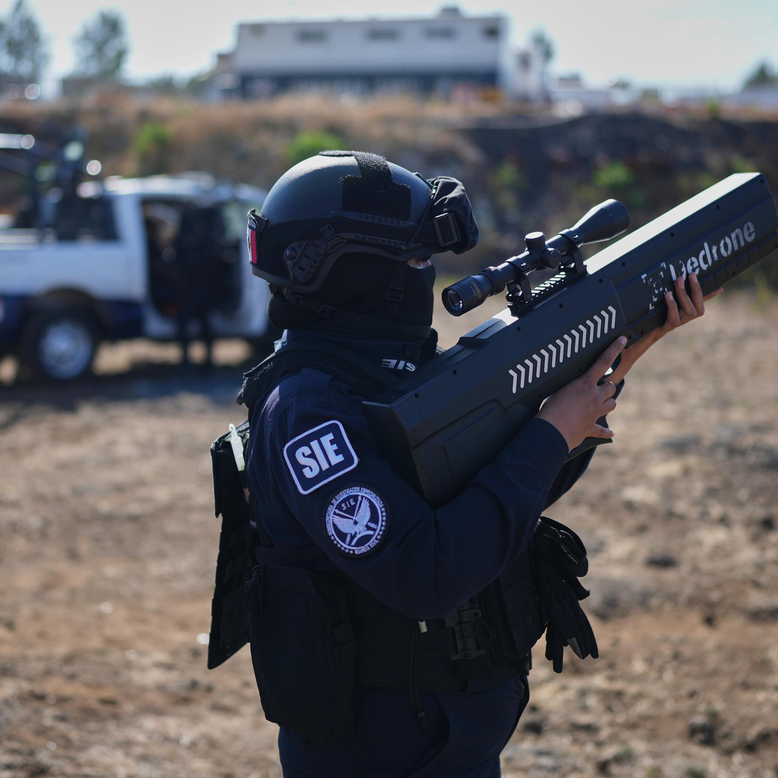 a person wearing a helmet and tectical gear holds a rifle-like weapon