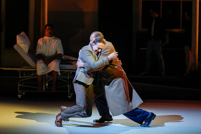 Production image: two men collapse in a hug.