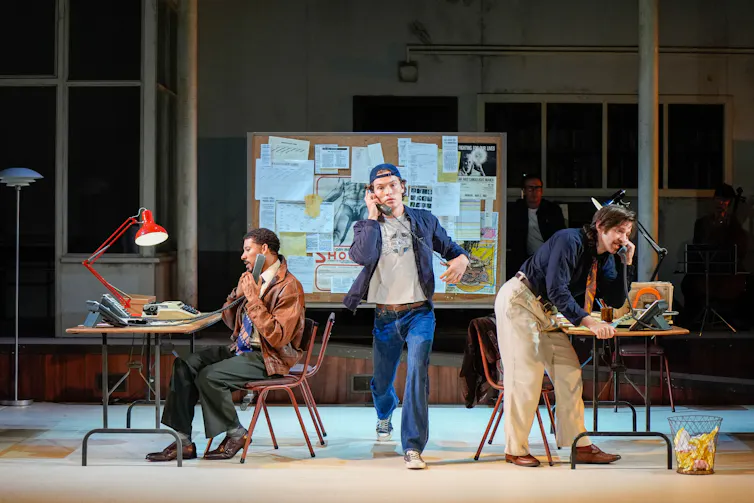 Production image: three young men in a 1980s office.