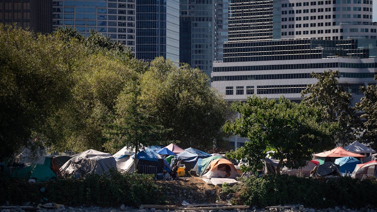 Campamento de tiendas con edificios urbanos al fondo