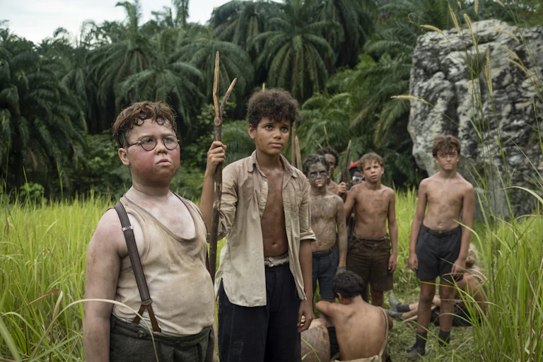 a group of boys, dirty and shirtless, in a jungle, with sticks