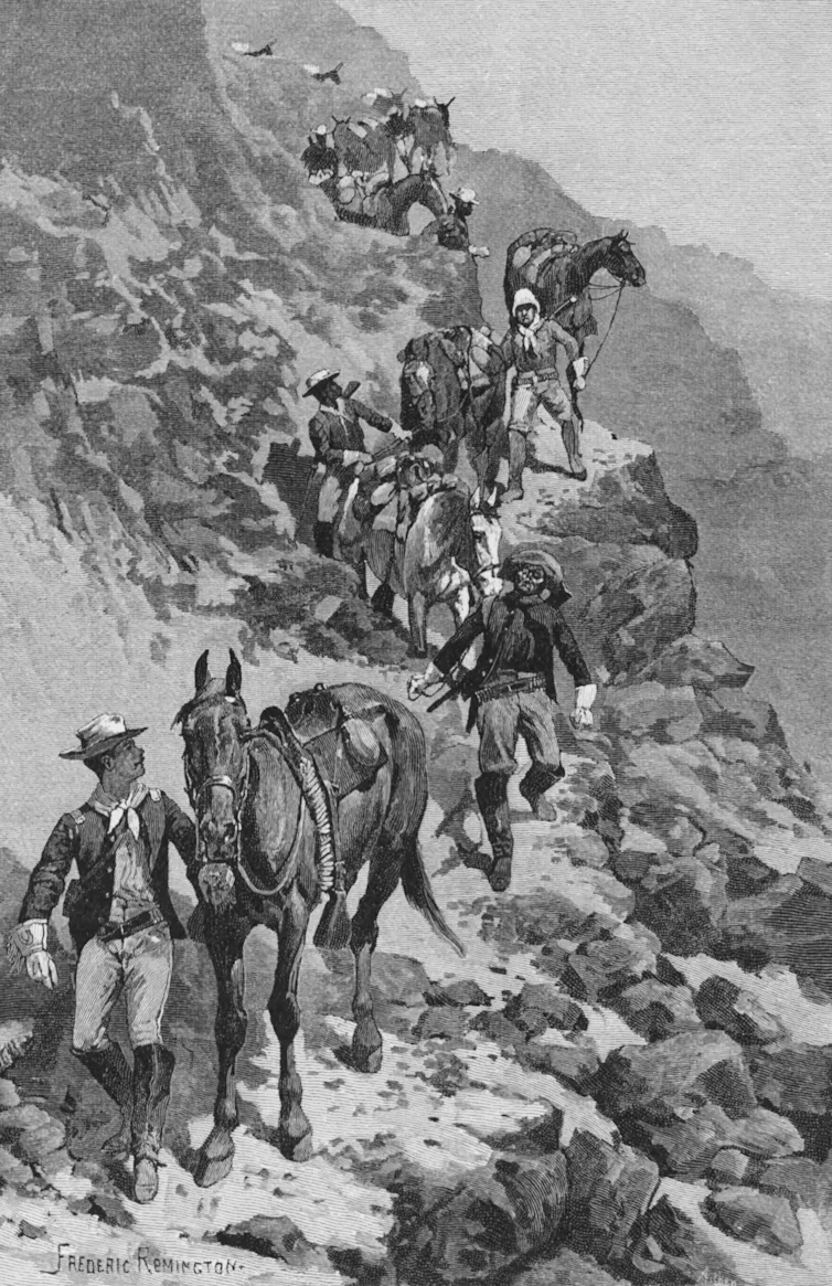 African American men in army uniforms lead horses around the bend of a jagged cliffside.
