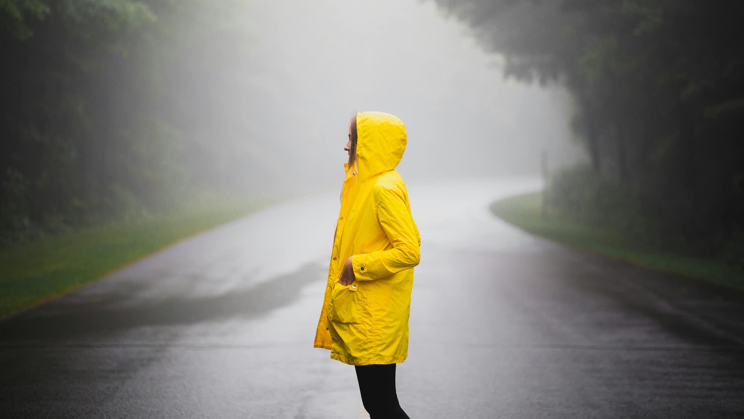A person wearing a yellow jacket in the rain.