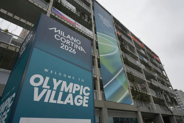 A sign reading 'Milano Cortina 2026 Welcome to Olympic Village'