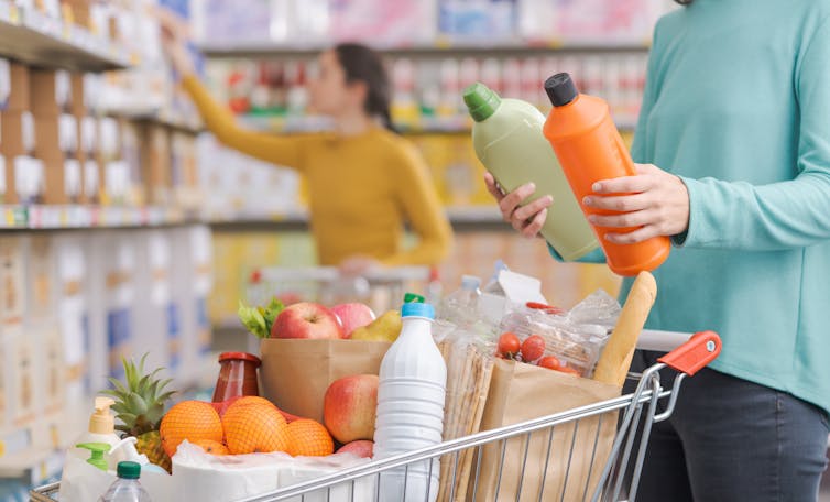 woman shopper with trolley checking two bottles