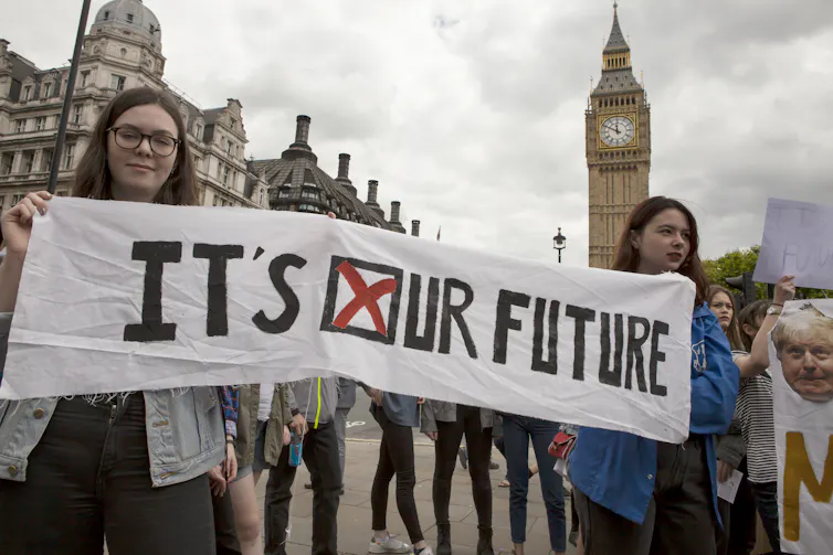 Young people holding a sign reading 'it's our future' in front of the Houses of Parliament.