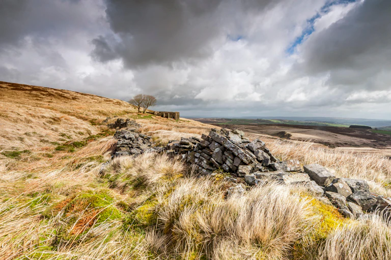 A wild moorland landscape under scudding clouds in a gun metal sky.