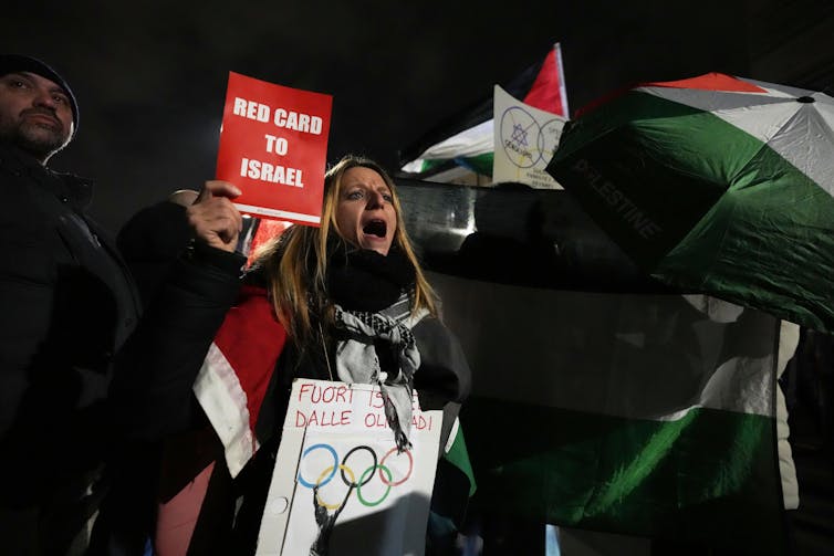 La prohibición del COI a un atleta ucraniano por su casco revela un preocupante doble rasero 1 Los manifestantes sostienen banderas palestinas y carteles que dicen
