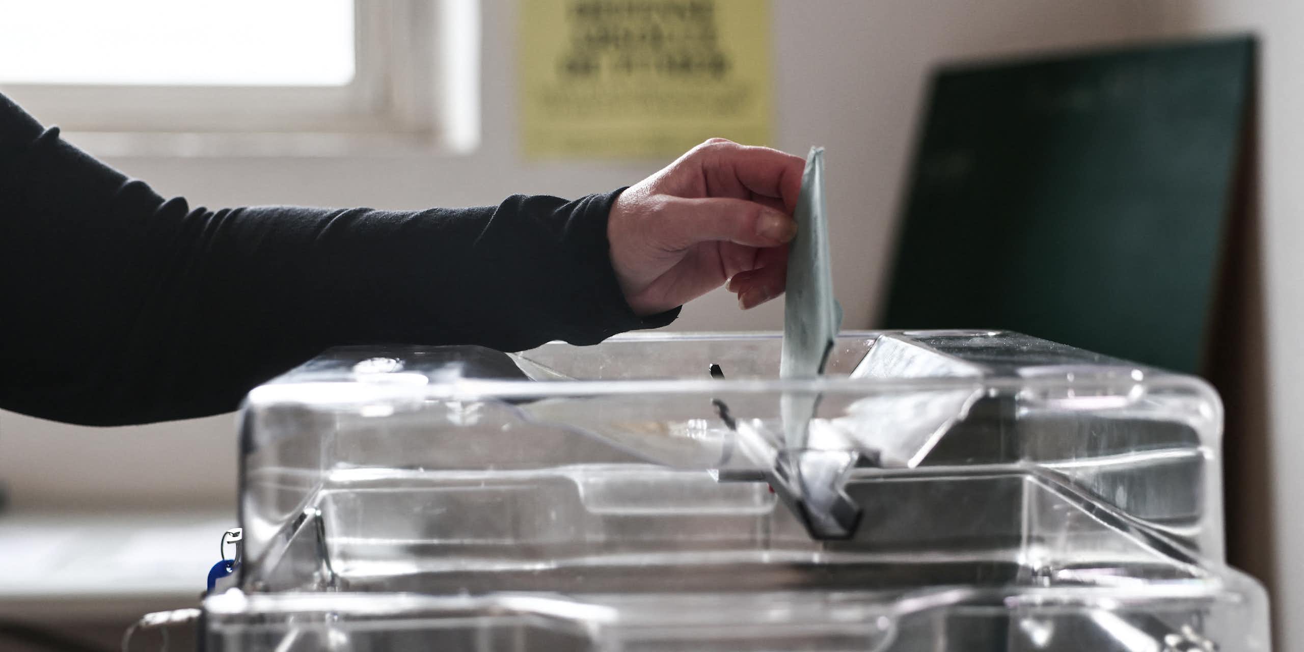 Photo d’une personne glissant un bulletin dans une urne.