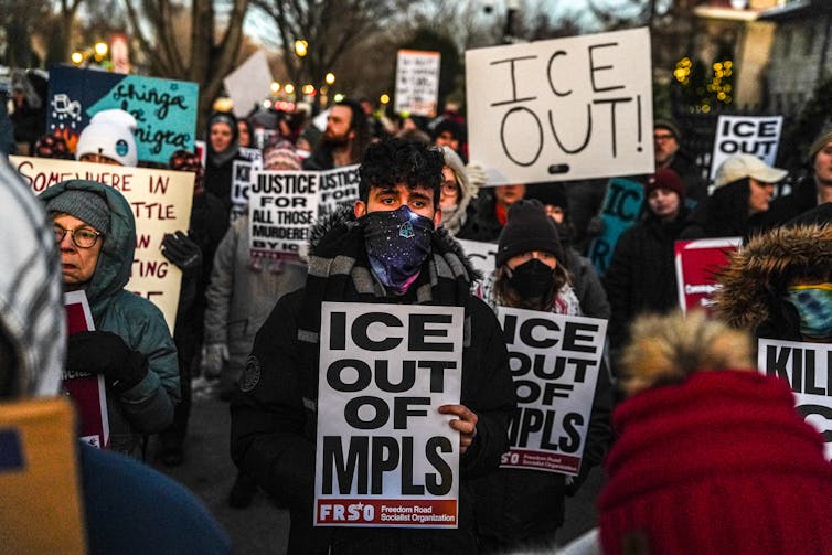 people at a protest carry signs that read ice out