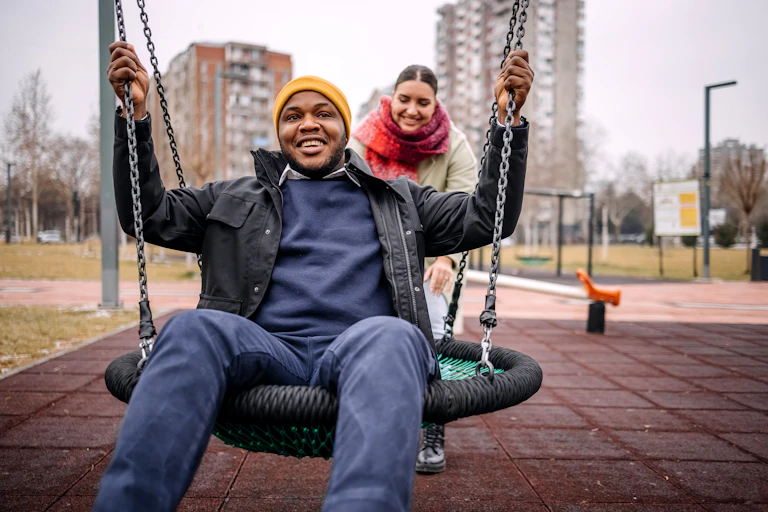 Young adults enjoying playing on a swing