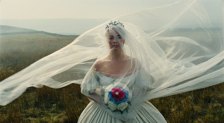 Production image: Cathy in a white wedding dress and veil.