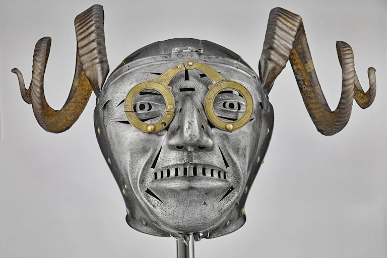 Front view of a steel helmet with golden spectacles and ram horns.