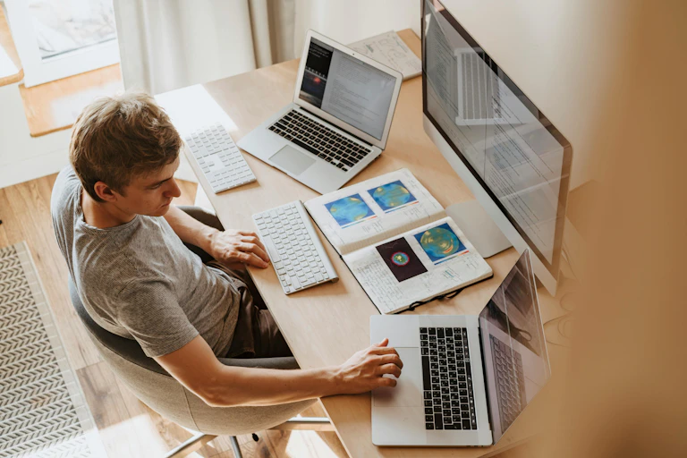 Man using 3 computer screens at once