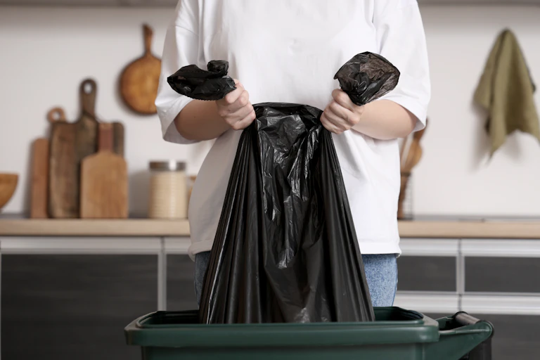 mains qui tiennent une poubelle noire