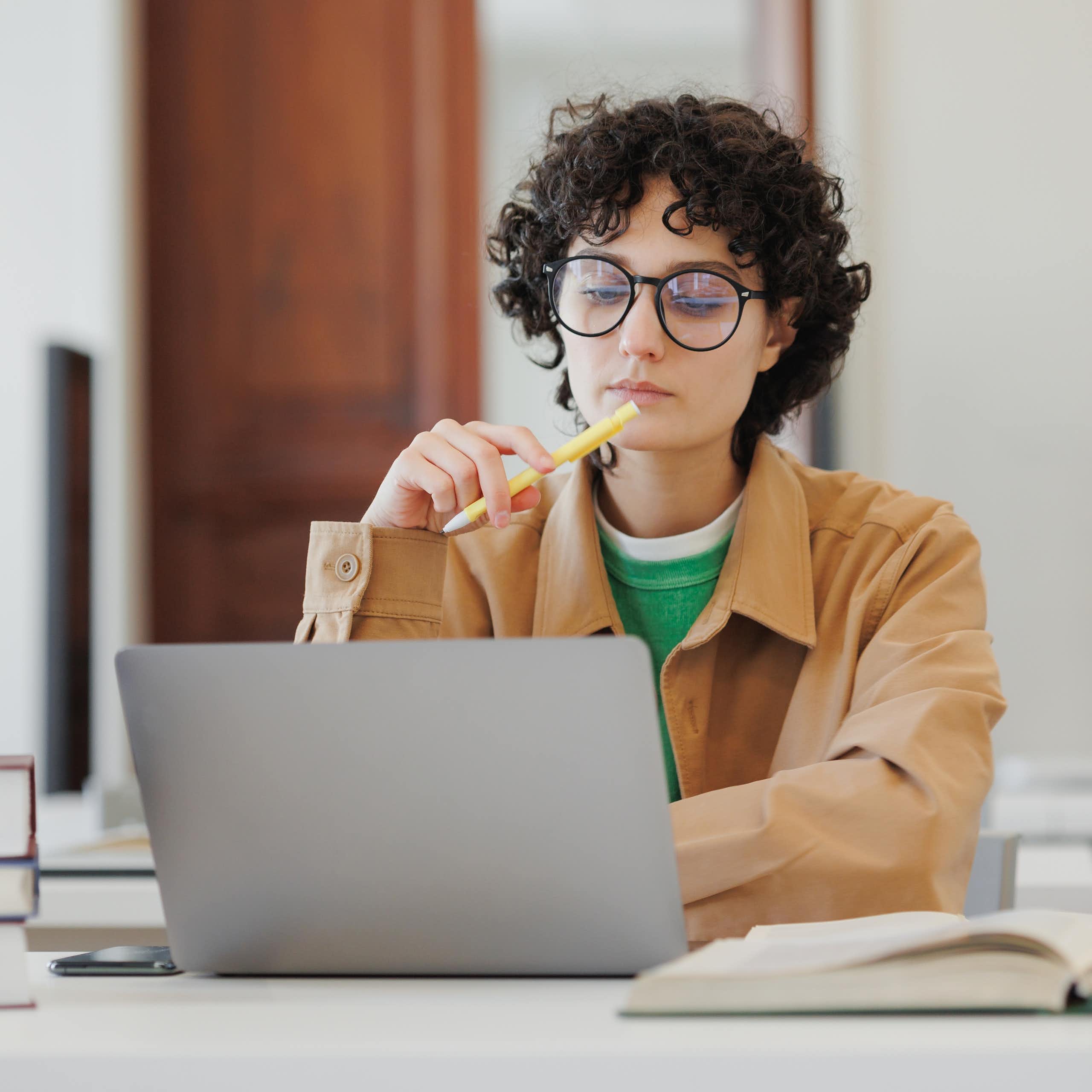 Una joven pensativa ante un ordenador portátil