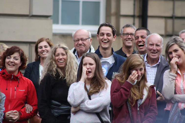 A crowd of people laughing – some dabbing their eyes.