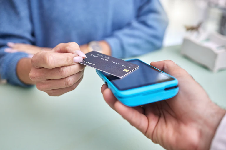 Woman paying for goods or services, tapping card onto screen