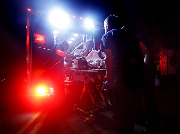 Paramedics tending to a patient on a gurney outside an ambulance at night.