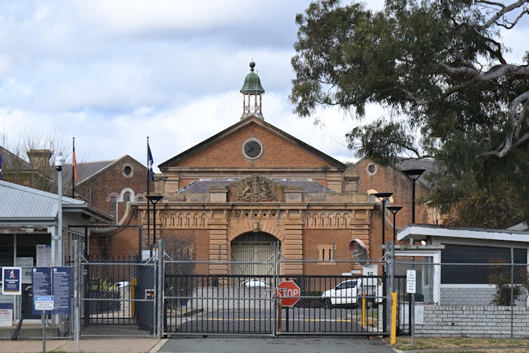 A large brick prison building behind a gate