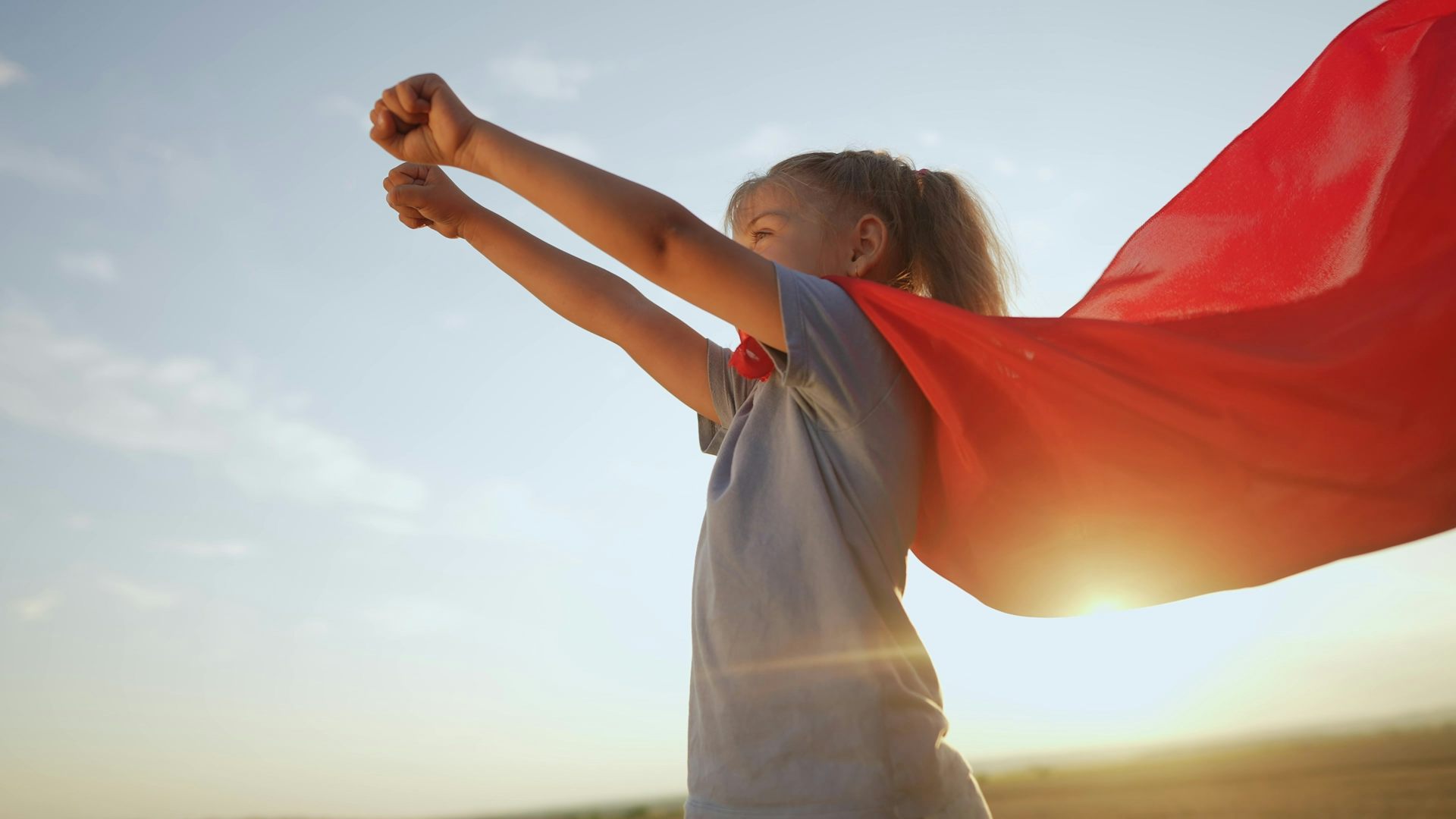 Une petite fille avec une cape de super-héroïne.