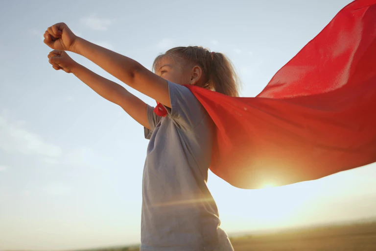 Une petite fille avec une cape de super-héroïne.
