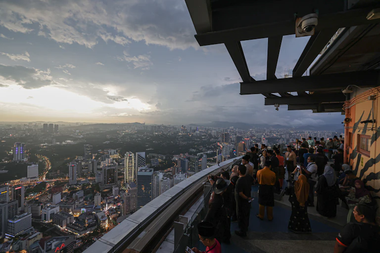 People gather to see the new crescent Moon on a building in Kuala Lumpur.