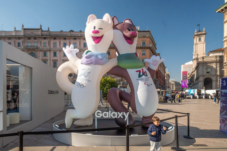 Two mascots of the Milano Cortina Winter Olympic Games in a town square