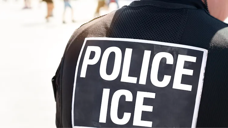 View from behind of an ICE agent's vest that reads POLICE ICE