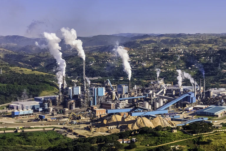 A paper making factory with clouds of smoke coming out of towers