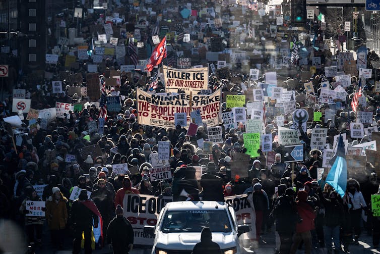 A huge crowd of protesters carrying anti-ICE signs.