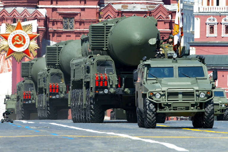 a line of large green vehicles carry large missiles