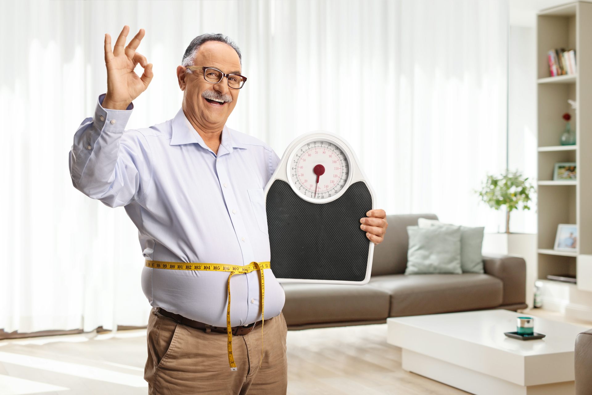 Happy mature man with a weight scale and a measuring tape
