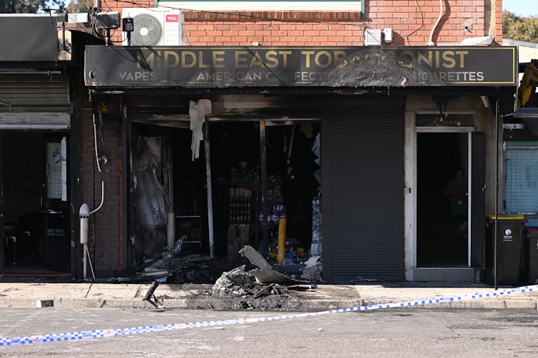 The exterior of a burned down shop front of a tobacco store