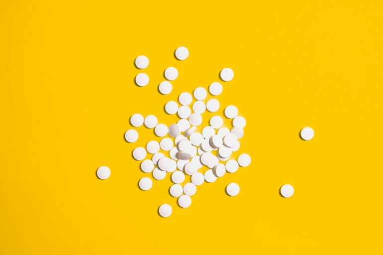 Round white pills on yellow background