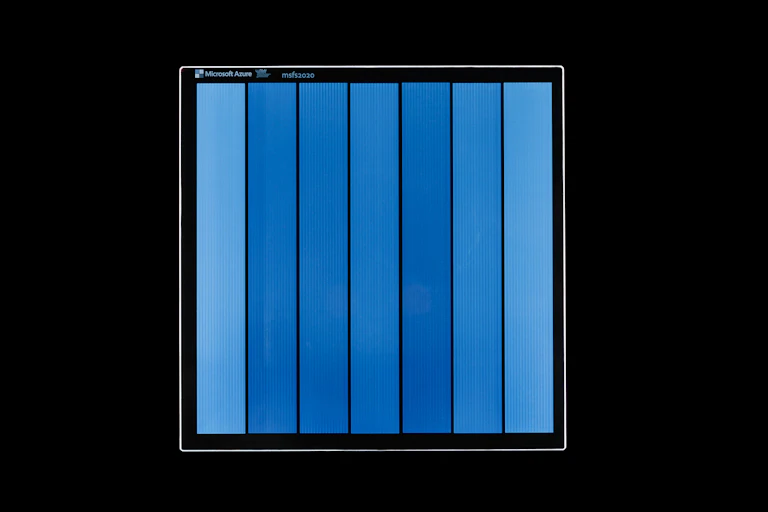 Photo of glass square with blue stripes against a black background.