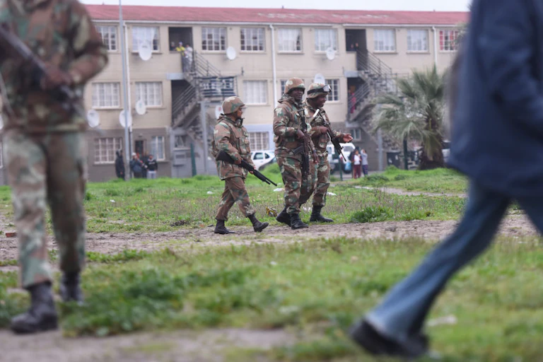 People in camouflage uniform, holding weapons, outside an apartment block
