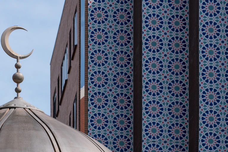Close up of the dome of the East London Mosque on Whitechapel Road, with the decorative mosaic tiles of the London Muslim Centre to its side