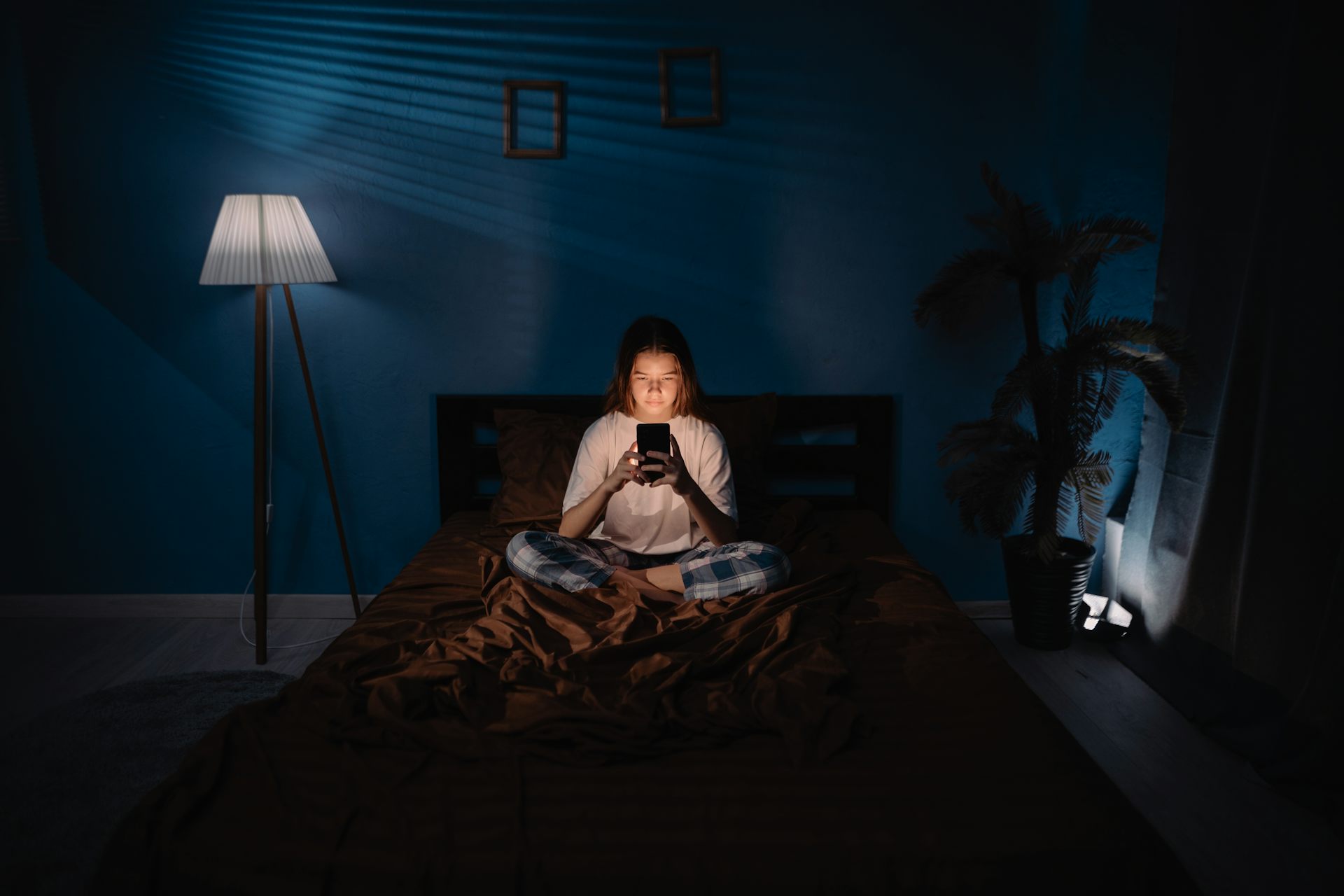 Girl on phone in dark bedroom