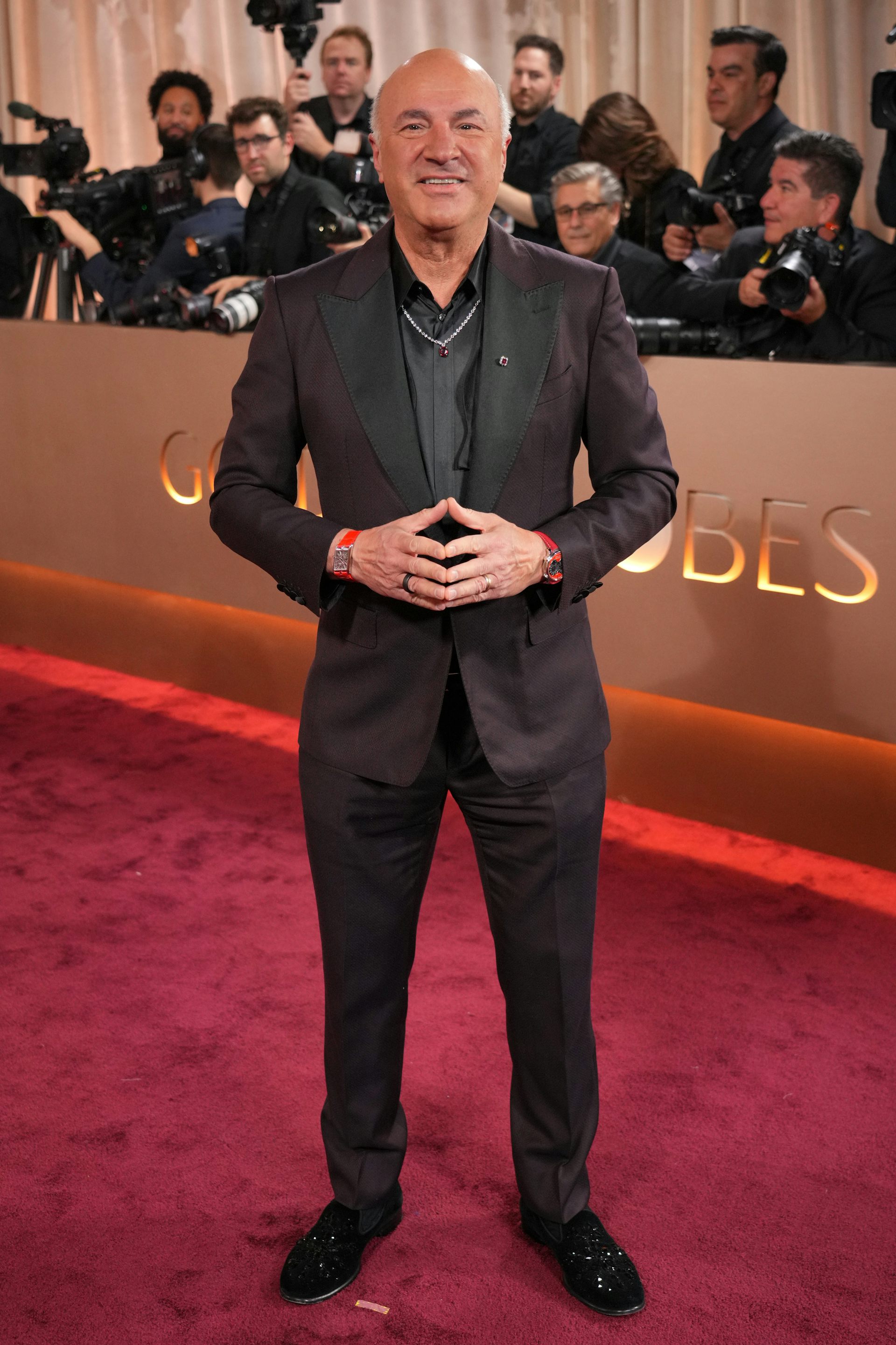 Un hombre con traje sonríe ampliamente mientras los fotógrafos están detrás.