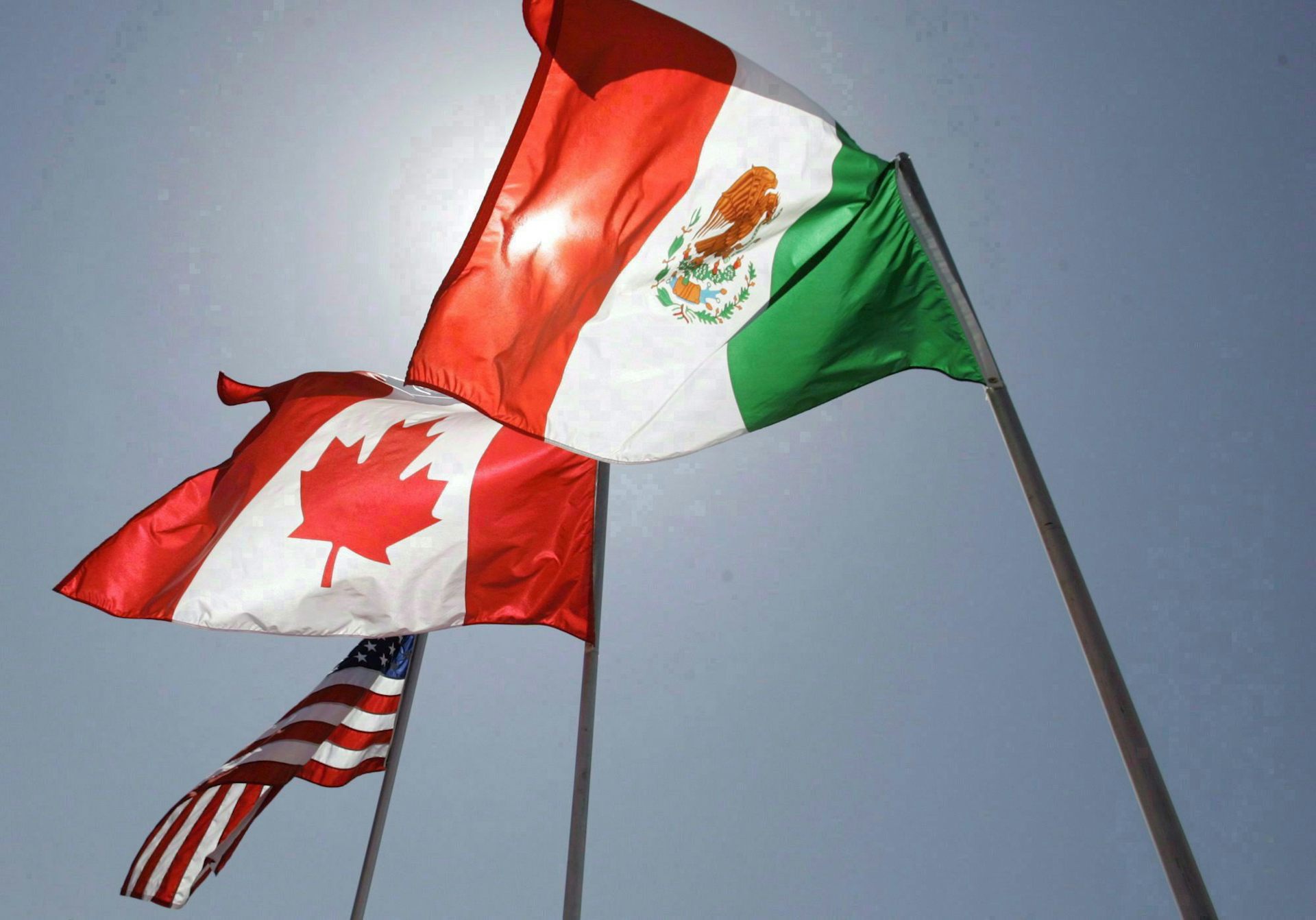 Banderas de México, Canadá y Estados Unidos en postes.