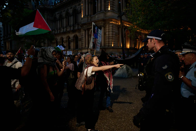 A protester points towards police amid a nighttime rally
