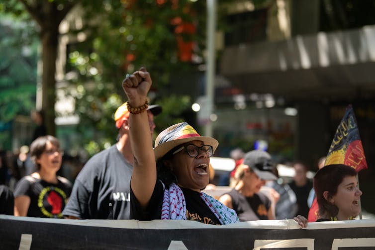 An Indigenous woman marching with one fist in the air