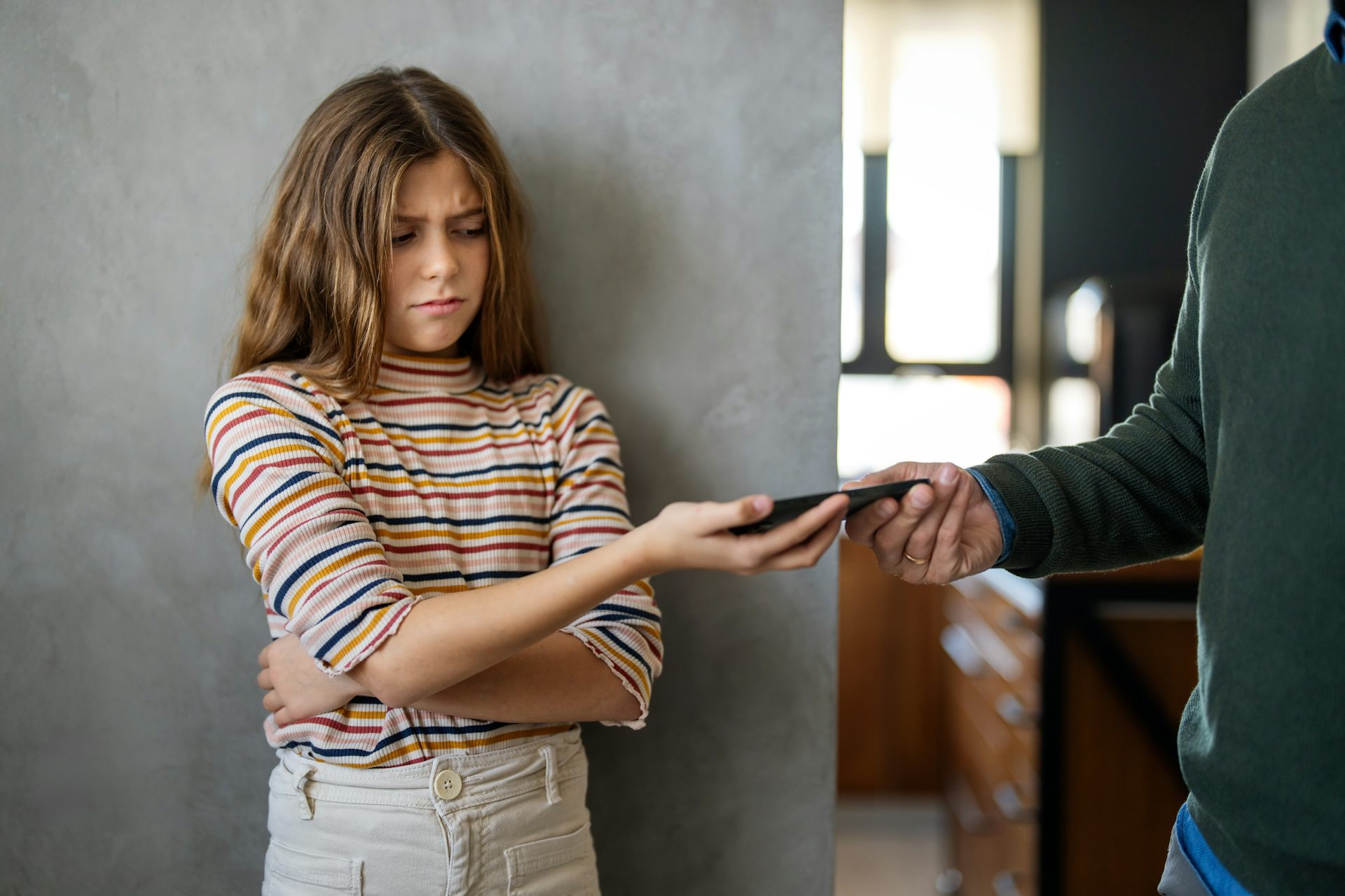 Girl unhappily handing over phone