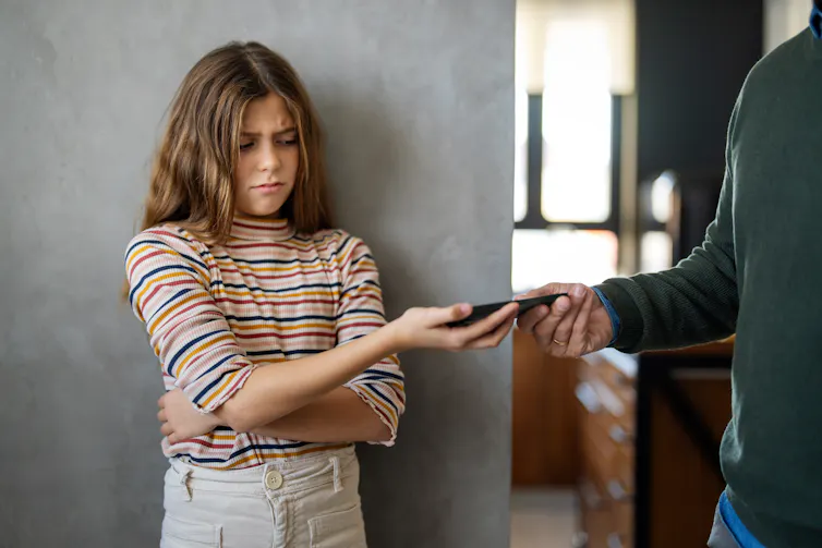 Girl unhappily handing over phone