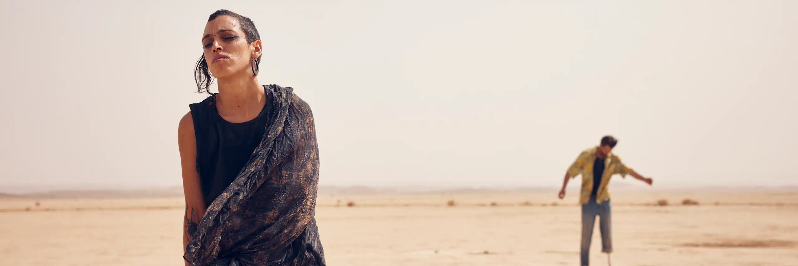 Dos personas bailan en el desierto.