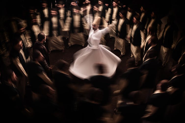 ¿Y si dejáramos todo y nos fuéramos al desierto? 'Sirat' y la tentación de desaparecer de uno mismo 2 Una imagen de un hombre bailando mientras gira rodeado de otros hombres.