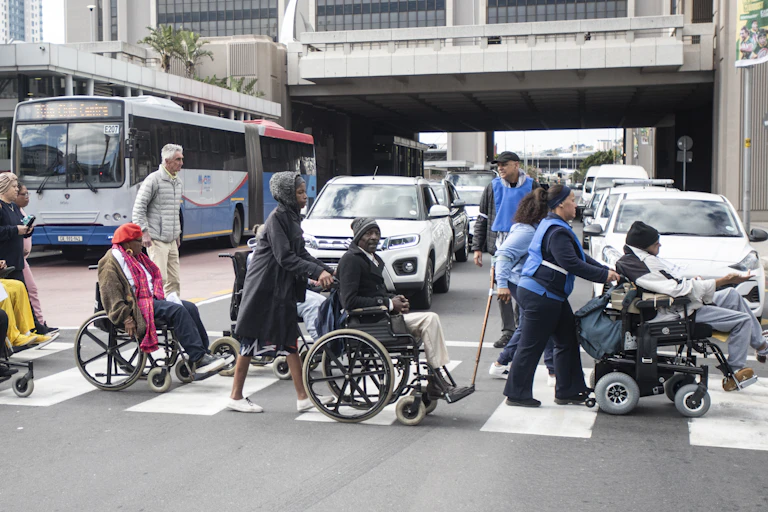 People on wheelchairs crossing a busy road