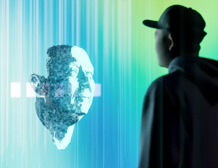 A man looks at a hologram of a human face