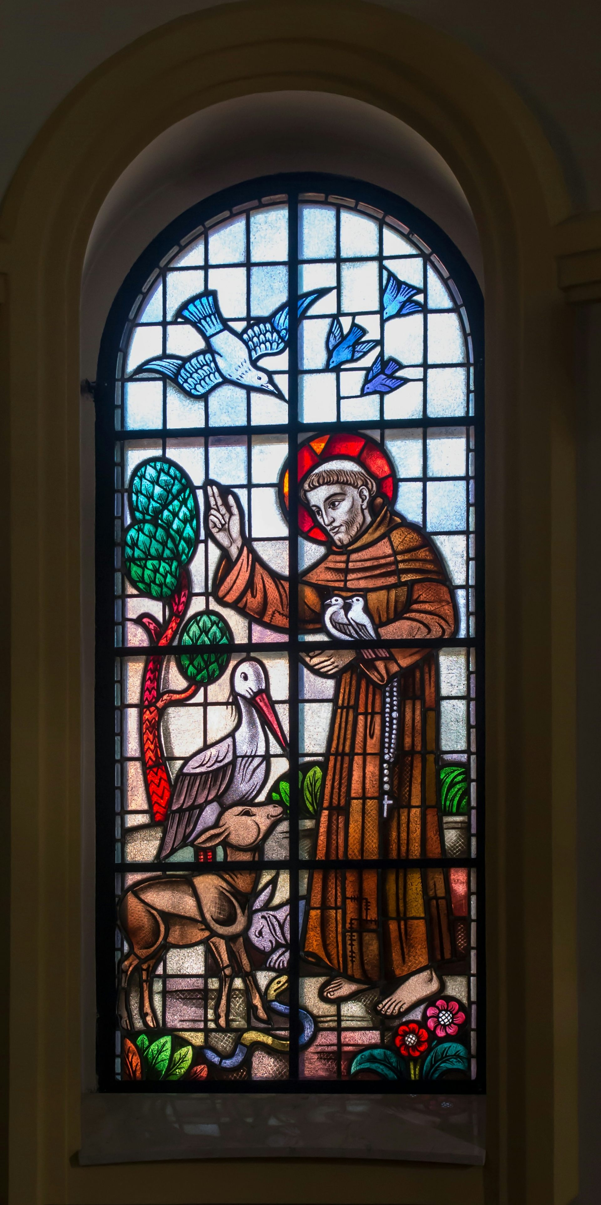 A stained glass window in a church depicting St Francis of Assisi with birds and animals.